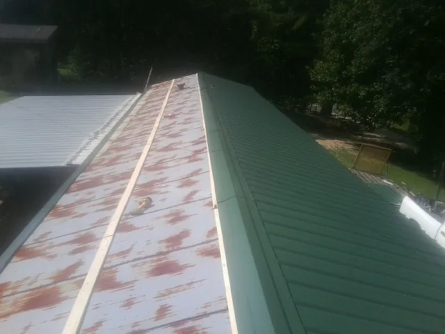 Old rusted panels beside newly installed green metal roofing — Wind Damage Roof Repair by Roofing Brothers in Brooker