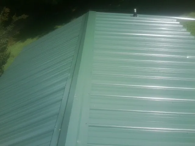 New green metal panels meeting at the ridge of a roof — Flat Roof Repair work by our crew in Brooker