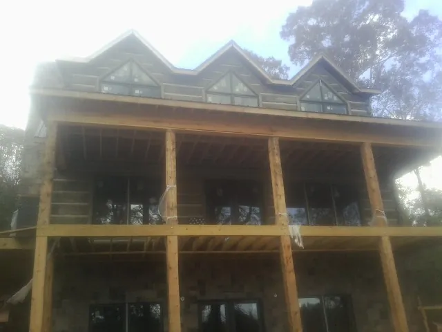Dormers and porch framing on a large log home under construction — Roof Coating work by our crew in Brooker