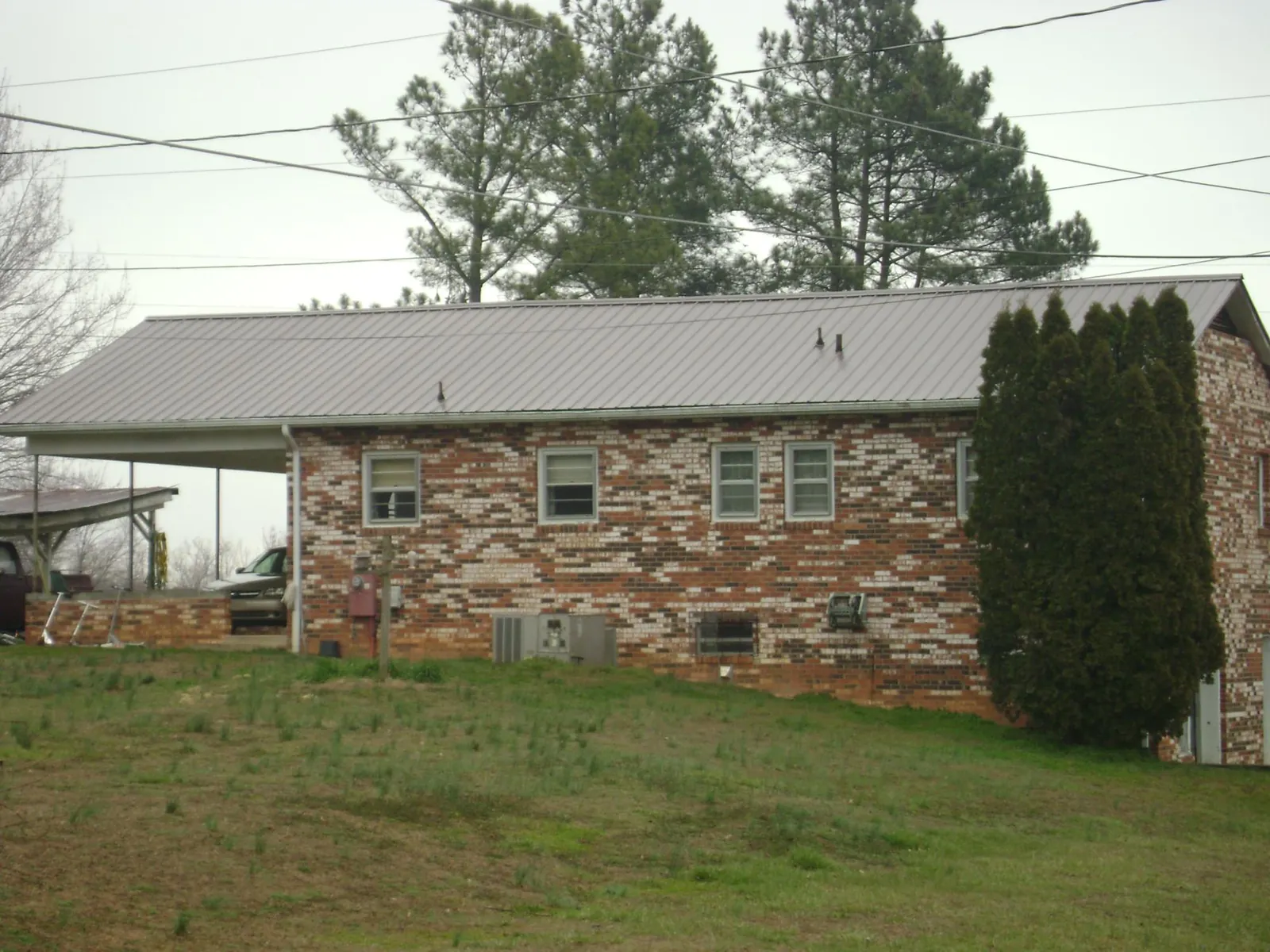 Gray metal roof on a brick split level home with a carport in Brooker