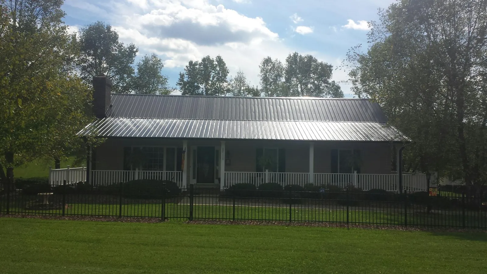 Gray metal roof on a brick ranch with a full width front porch — Gutter Guard Installation work by our crew in Brooker