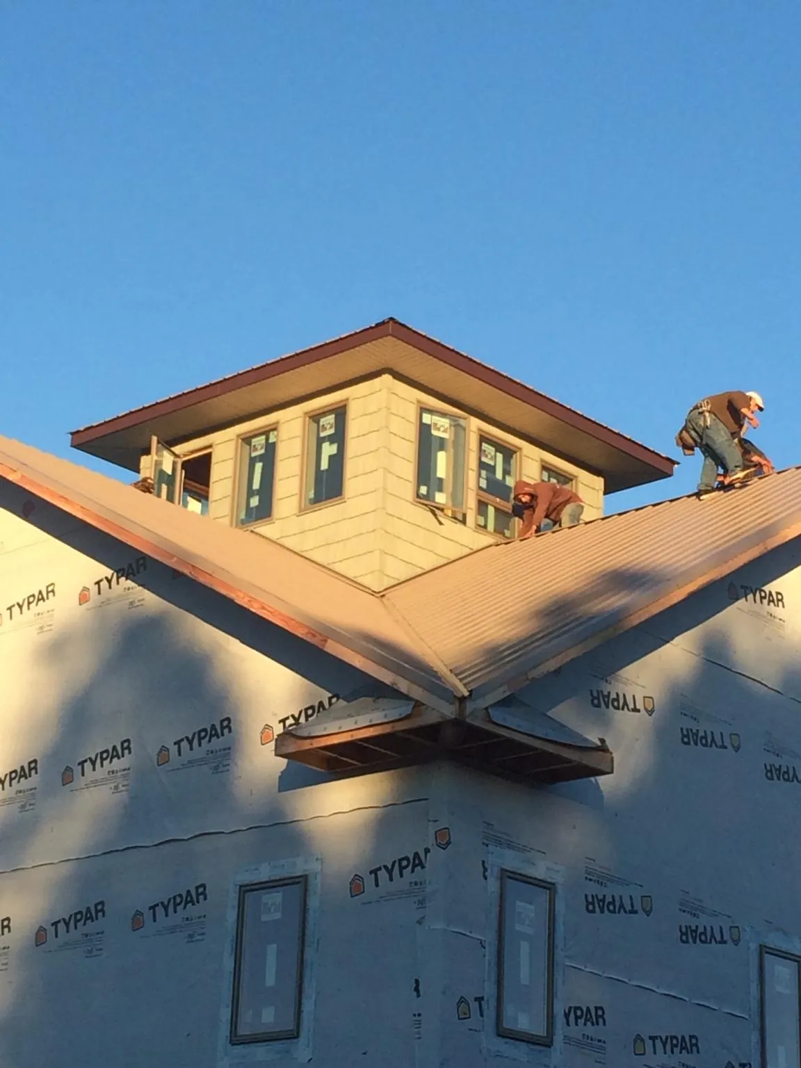 Roofers working around a rooftop cupola on a new metal roof at sunset — Roof Waterproofing in Brooker by Roofing Brothers